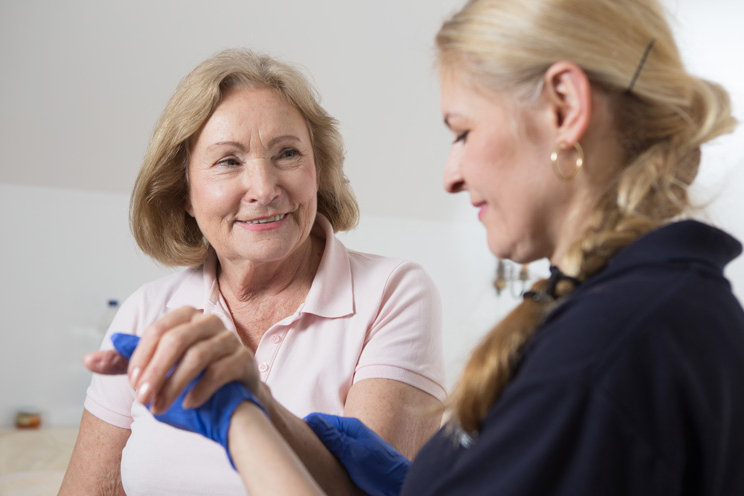 Hauskrankenpflegerin hält Klientin am Arm