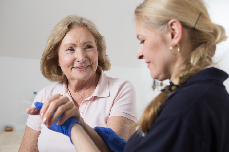 Hauskrankenpflegerin hält Klientin am Arm