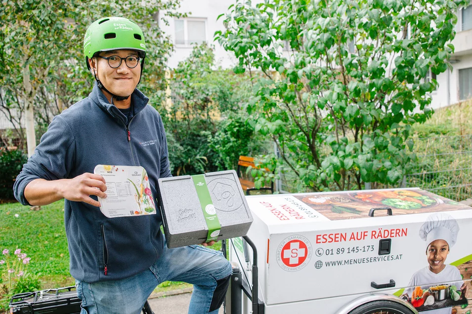 Essen auf Rädern Zusteller mit Essensbox auf Zustellfahrrad